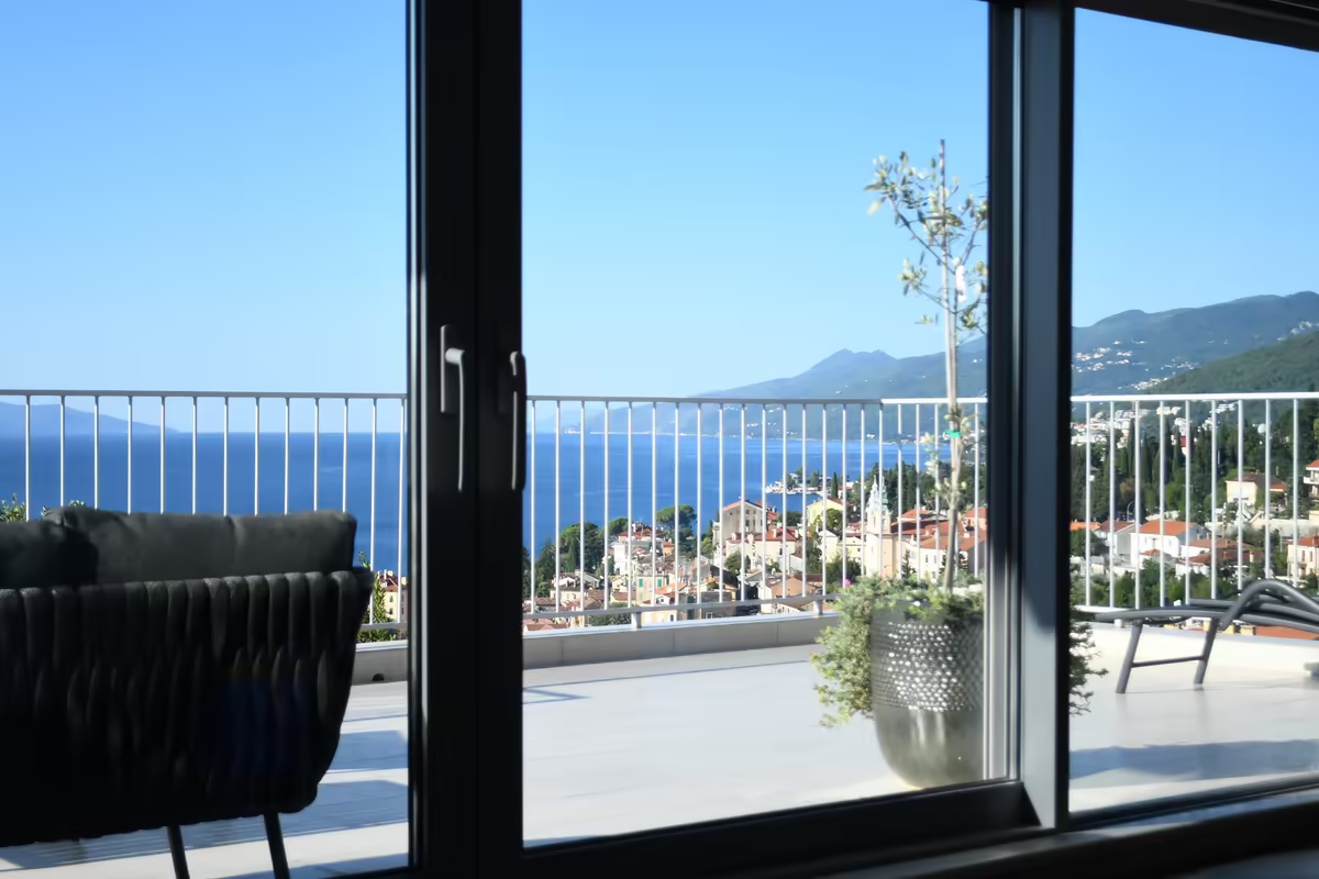 Baie vitrée ouverte sur une terrasse avec vue sur la mer et la côte